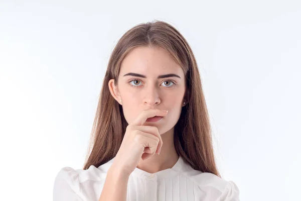 Thoughtful young woman looks straight and keeps a hand near the lips isolated on white background — Stock Photo, Image
