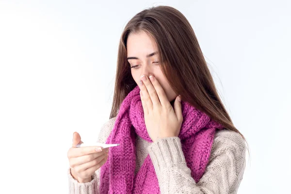 Девочка в шарфе заболела и выглядит температурно изолированной на белом фоне — стоковое фото