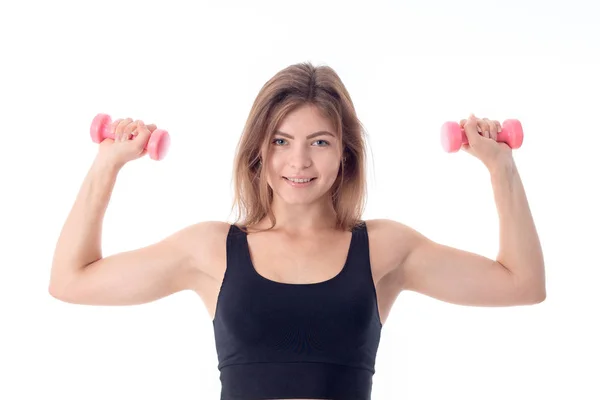 Chica deportiva sonriendo y apretando sus dos brazos con mancuernas —  Fotos de Stock