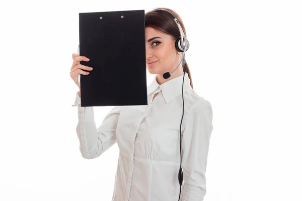 Bela jovem mulher de negócios trabalhando em call center com fones de ouvido e microfone sorrindo e esconder o rosto atrás de uma placa isolada no fundo branco — Fotografia de Stock