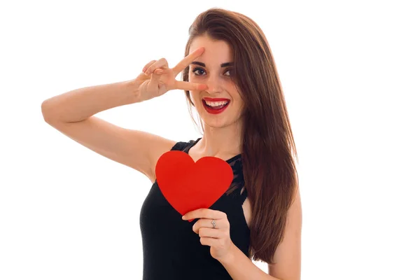Wesoła brunetka dziewczyna w czarnej sukni z ładny makijaż Świętuj Walentynki z czerwonym sercem w jej ręce na białym tle — Zdjęcie stockowe