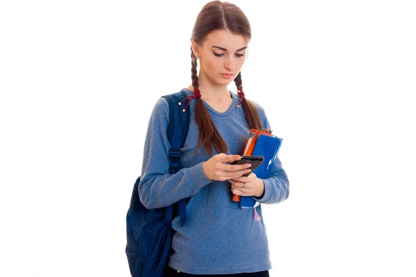 Triste studentessa intelligente con zaino sulle spalle e cartella per notebook nelle sue mani guardando verso il basso isolato su sfondo bianco — Foto Stock