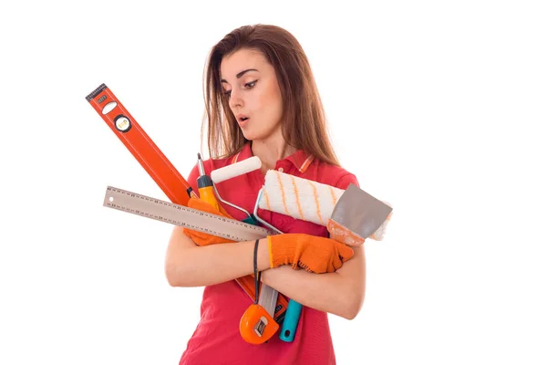 Retrato de joven morena sorprendida edificio mujer en uniforme rojo con herramientas en las manos hace renovación aislada sobre fondo blanco — Foto de Stock