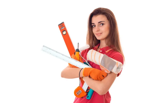 Retrato de joven atractiva morena edificio mujer en uniforme rojo con herramientas en las manos hace renovación y mirando a la cámara aislada sobre fondo blanco — Foto de Stock