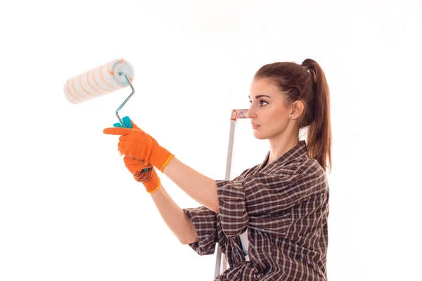 Portrait de jeune femme brune concentrée bâtiment avec rouleau de peinture dans les mains rend la rénovation isolée sur fond blanc — Photo