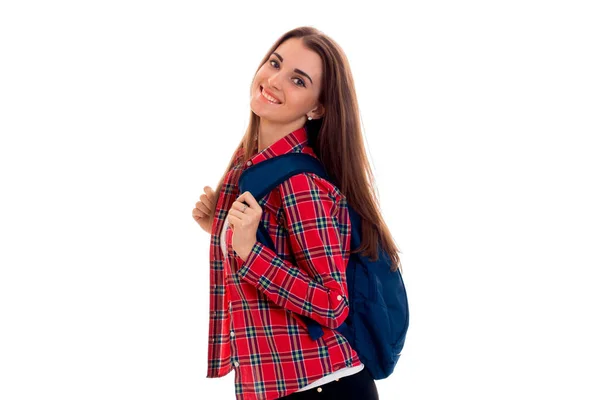 Bella ragazza sorridente in una camicia scozzese con uno zaino sulla schiena è — Foto Stock