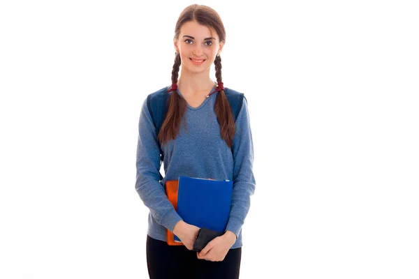 Linda adolescente se para con coletas en chaqueta azul sosteniendo una carpeta y sonriendo —  Fotos de Stock