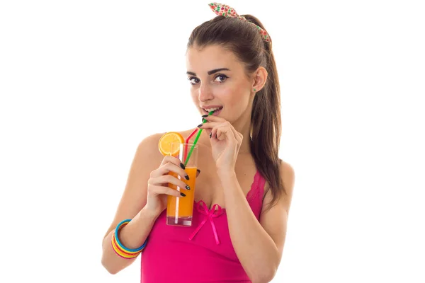 Une jeune fille dans un t-shirt lumineux tenant un verre de jus et le boire — Photo