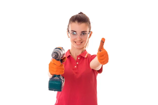 Sonriente chica joven se estira en un taladro de mano y muestra la clase de aislado sobre fondo blanco — Foto de Stock