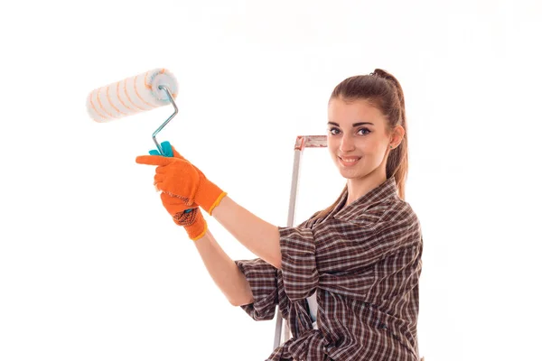 Uma jovem menina em uma camisa xadrez sorrindo e segurando um rolo para pintar paredes isoladas no fundo branco — Fotografia de Stock