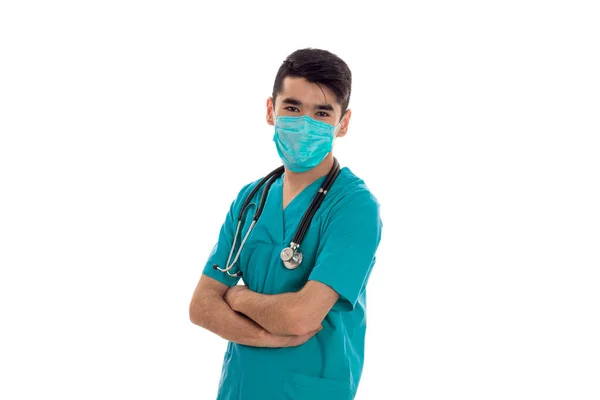 Młody lekarz w chuście na jego twarzy założonymi rękoma makro na białym tle — Zdjęcie stockowe