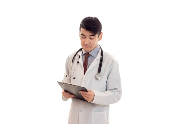 A young doctor in a white lab coat with a stethoscope and looking at Tablet isolated on white background — Stock Photo, Image