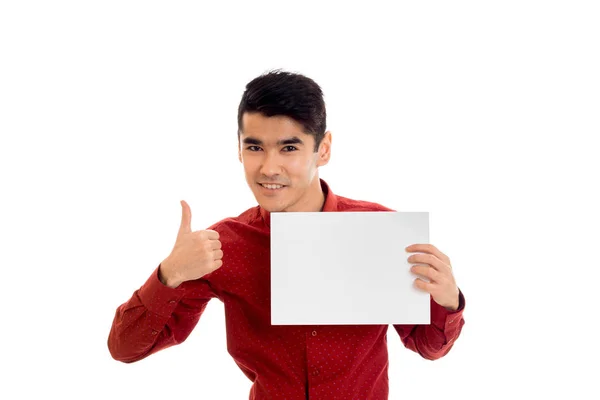 Um jovem com uma camisa vermelha segurando um papel branco isolado no fundo branco — Fotografia de Stock