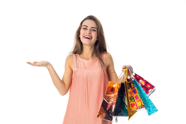 Chica extiende su mano y mantiene una gran cantidad de paquetes de colores con compras aisladas sobre fondo blanco — Foto de Stock