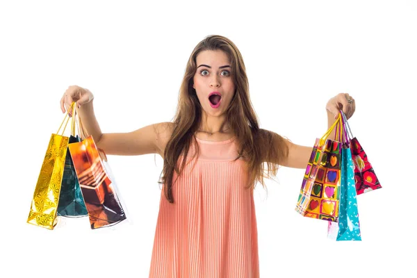 Fiatal lány hatalmas meglepetés tartja, az oldalán világos táskák giveaways van elszigetelt fehér background — Stock Fotó