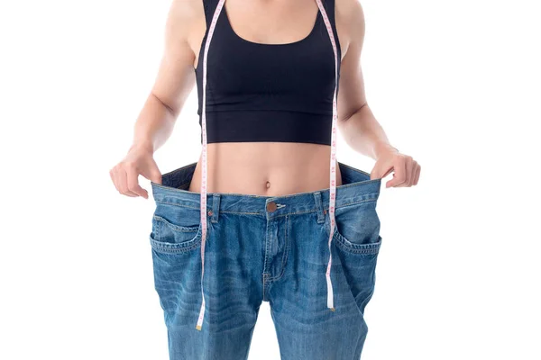 Slender girl stands in huge denim pants close-up — Stock Photo, Image