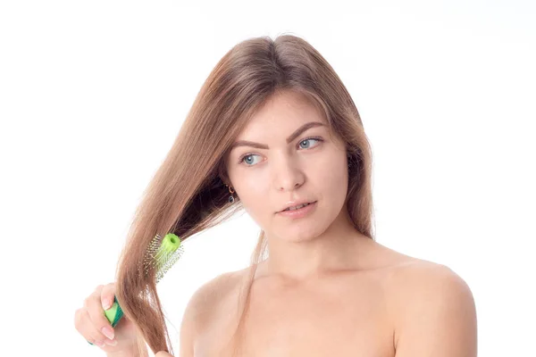 Meisje kammen van haar haren en kijkt naar geïsoleerde op witte achtergrond — Stockfoto