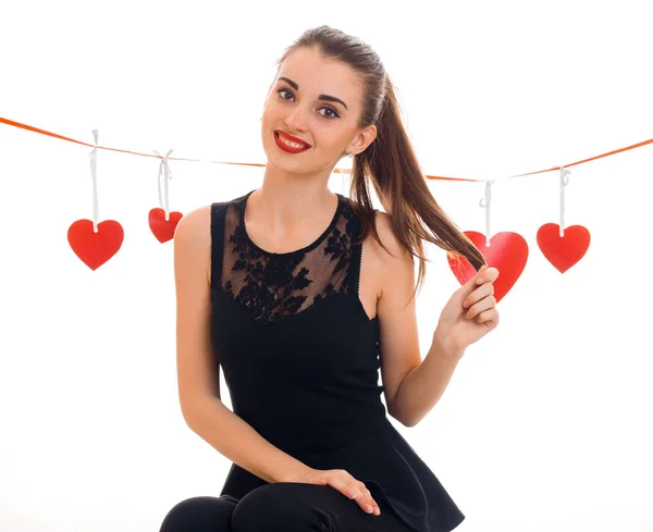 Foto quadrata di giovane donna bruna allegra con cuore rosso in studio sorridente sulla macchina fotografica isolata su sfondo bianco. Concetto di San Valentino . — Foto Stock