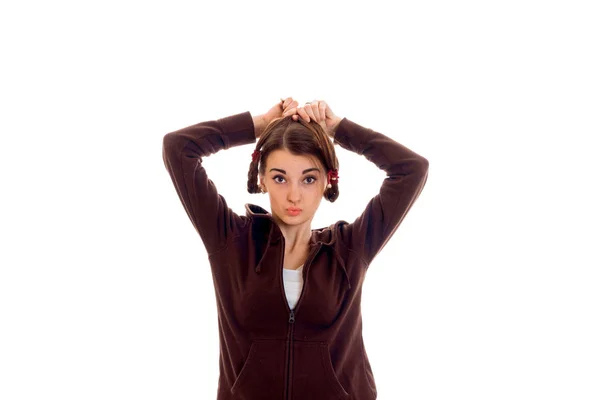 Jonge grappige brunette student meisje in bruin sport kleding met pigtails poseren op camera geïsoleerd op witte achtergrond — Stockfoto