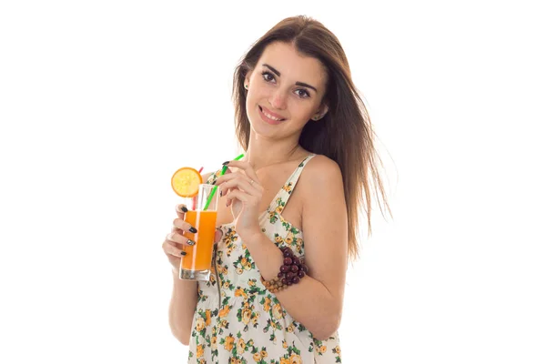 Young beautiful brunette girl in sarafan with floral pattern drinks orange cocktail and smiling on camera isolated on white background — Stock Photo, Image