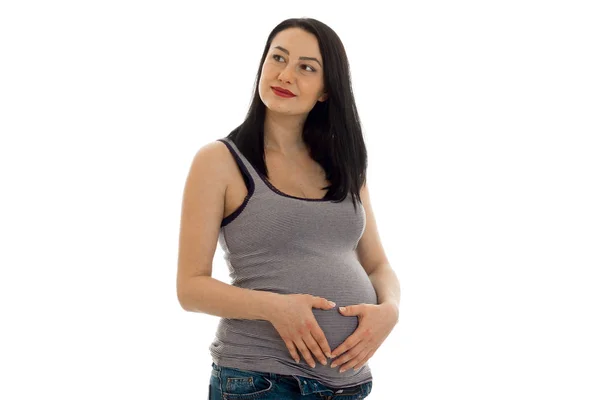 Preciosa morena embarazada tocando su vientre y mirando hacia otro lado aislado sobre fondo blanco — Foto de Stock