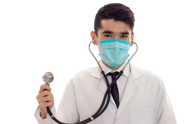 Ritratto di giovane bruna uomo medico i maschera con stetoscopio guardando la fotocamera isolata su sfondo bianco — Foto Stock