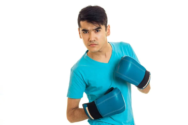 Porträt eines ernsthaften brünetten Boxers mit blauen Handschuhen, der isoliert auf weißem Hintergrund in die Kamera blickt — Stockfoto