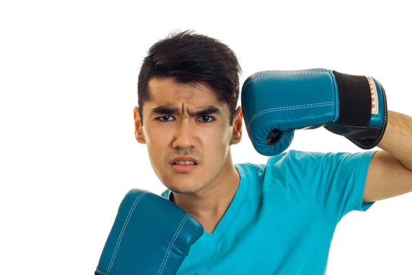 Porträt eines wütenden brünetten Boxers in blauen Handschuhen, der isoliert auf weißem Hintergrund in die Kamera blickt — Stockfoto