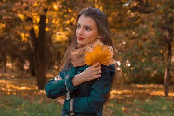 Fille réfléchie se tient dans la rue et tenant feuilles d'automne dans la main — Photo