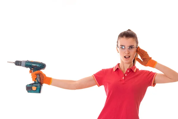 Молодая смешная брюнетка женщина строитель в форме с очками и дрель в руках сделать reovations изолированы на белом фоне — стоковое фото