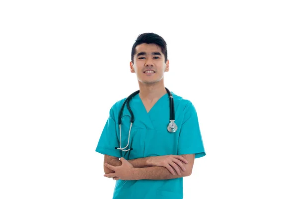 파란색 유니폼 흰색 배경에 고립 된 카메라에 웃 고 하는 그의 어깨에 청진 기를 행복 한 갈색 머리 청년 의사 — 스톡 사진