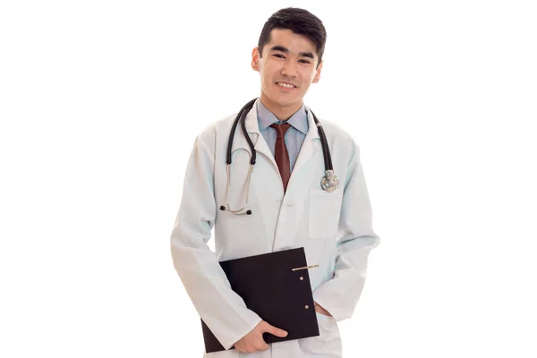 Jovem morena alegre homem médico em uniforme com estetoscópio em seus ombros sorrindo isolado no fundo branco — Fotografia de Stock