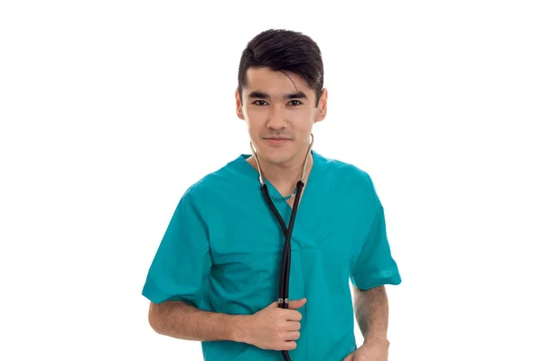 Genç esmer yakışıklı doktor mavi beyaz arka plan üzerinde izole kamera bakarak onun omuzlarında stetoskop ile üniforma — Stok fotoğraf