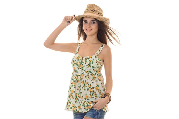 Молодая девушка в шляпе и красивой летней футболке встает прямо и смотрит на камеру на белом фоне — стоковое фото