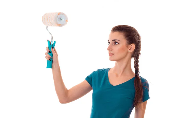 Uniforl koyu saçlı genç güzel kadın tadilat boya silindiri ile beyaz arka plan üzerinde izole elleri yapar — Stok fotoğraf