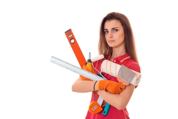 Unga allvarliga kvinna med mörkt hår i uniforl gör renoveringar med verktyg i händerna isolerad på vit bakgrund — Stockfoto