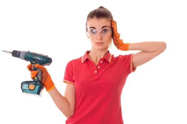 Giovane donna cutie con i capelli scuri in uniforl fa ristrutturazioni con trapano nelle sue mani isolato su sfondo bianco — Foto Stock