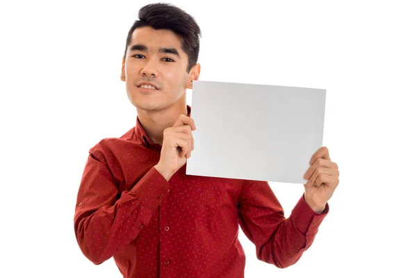 Πορτρέτο του κομψό νεαρό άνδρα στο κόκκινο t-shirt με άδειο πλακάτ στα χέρια του απομονώνονται σε λευκό φόντο — Φωτογραφία Αρχείου