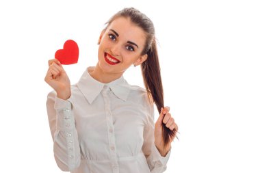 beyaz gömlek ve bir kalp şeklinde bir kart tutarak ve gülümseyen dudaklarında kırmızı ruj sevimli bir genç kız