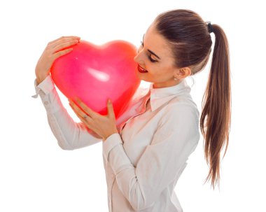 yana doğru ve tutan bir kuyruk ile genç bir kız duruyor bir kalp şeklinde büyük bir balon