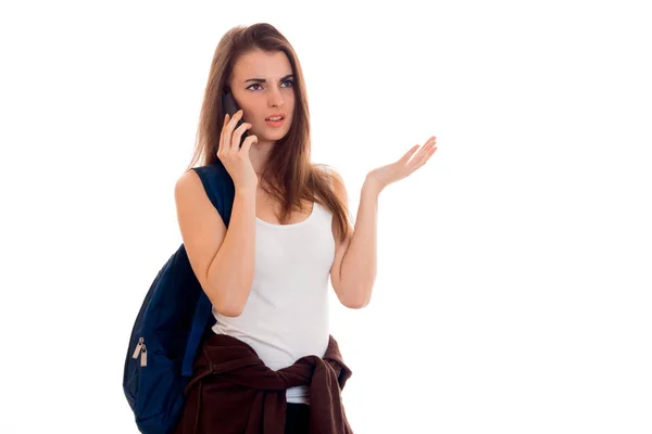 Молода дівчина в футболці і з рюкзаком на плечі з серйозною людиною, що розмовляє по телефону — стокове фото