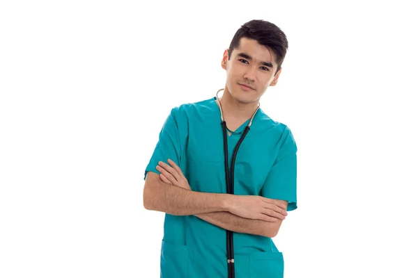 Jeune jolie brune homme médecin en uniforme bleu avec stéthoscope sur le cou posant sur caméra isolé sur fond blanc — Photo