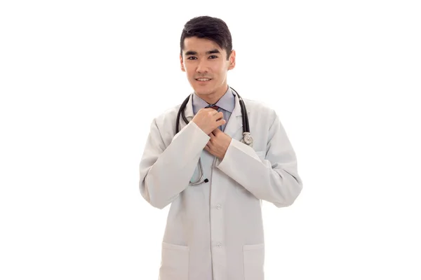 Bonito bonita morena masculino médico em uniforme com estetoscópio em seu pescoço posando na câmera isolada no fundo branco — Fotografia de Stock
