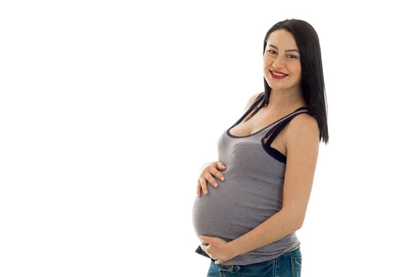 Unga gravid brunett flicka vidrör hennes mage isolerad på vit bakgrund — Stockfoto