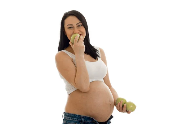Young pregnant brunette girl eats green apples isolated on white background — Stock Photo, Image