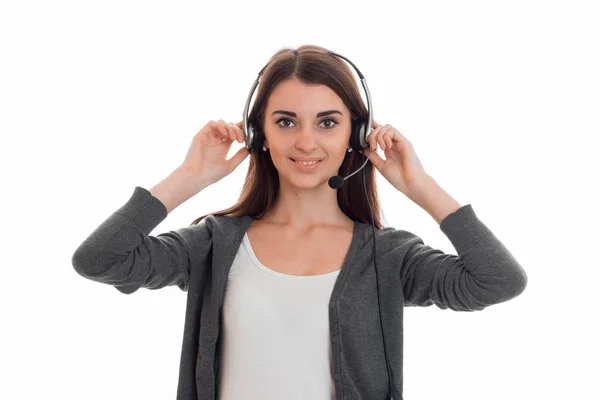 Smiling young girl holding up hands for the headphones on head and sotrit at camera Royalty Free Stock Photos