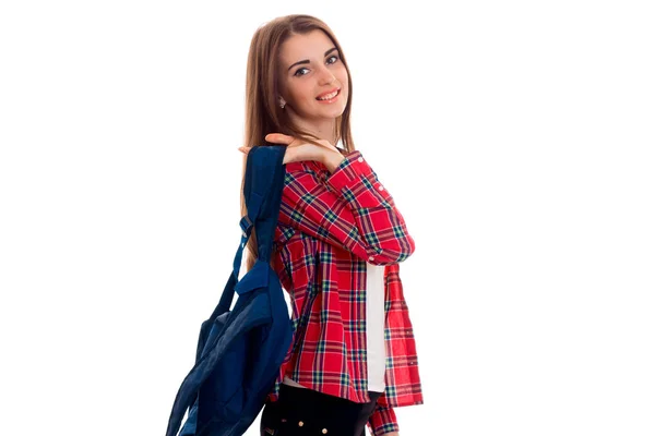 Młoda dziewczyna w czerwonej koszuli Plaid i z portfolio na ramionach stoi bokiem i uśmiechający się — Zdjęcie stockowe