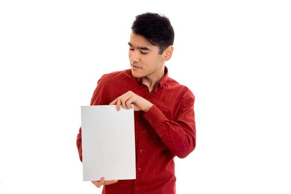 Um jovem com uma camisa vermelha segurando uma folha branca de papel — Fotografia de Stock