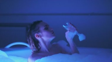 Banyo ve Şampanya köpüğü ile sıcak küvette ile rahatlatıcı sevimli genç kadın