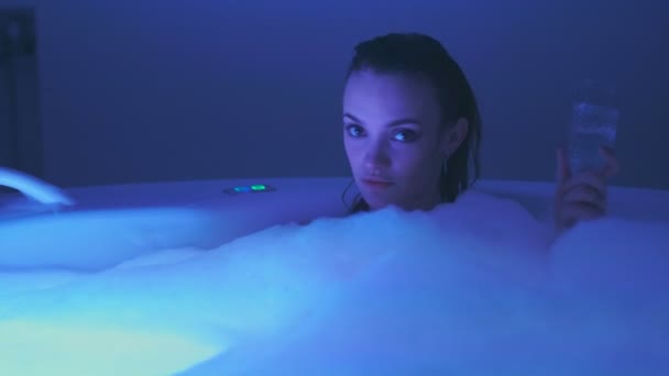 Lustful jovem mulher tomar banho e relaxar com um copo de champanhe na banheira de hidromassagem com espuma — Vídeo de Stock